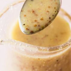 a spoon with some food in it on top of a glass jar filled with liquid