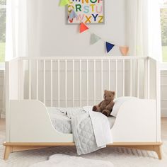 a teddy bear sitting on top of a white bed in a child's room