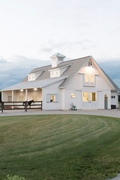 a large white barn sitting on top of a lush green field