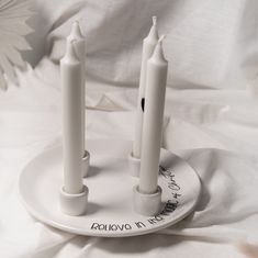 three white candles sitting on top of a plate