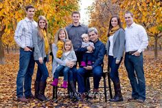 a group of people standing next to each other in front of trees with leaves on the ground