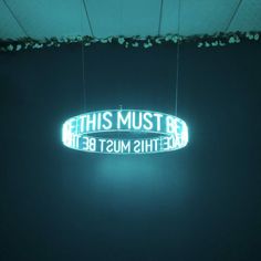 a neon sign hanging from the side of a wall that says, this must be