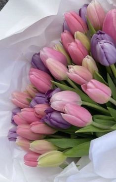 a bouquet of pink and purple tulips sitting on top of white paper