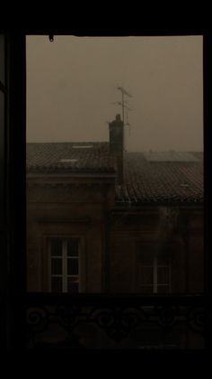 the view from an open window shows a building with a clock tower in the distance