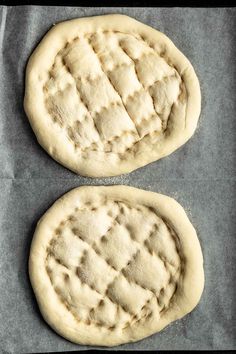 two uncooked pizza doughs on a baking sheet