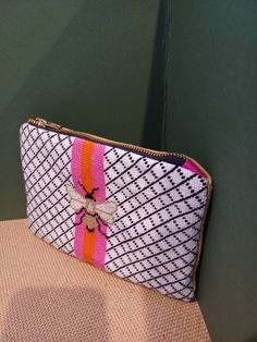 a white and pink purse sitting on top of a brown chair next to a green wall