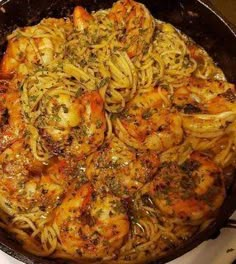 a pan filled with pasta and shrimp on top of a stove