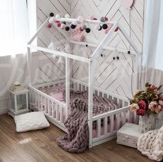 a white dollhouse bed with pink and black accessories on the floor next to a window