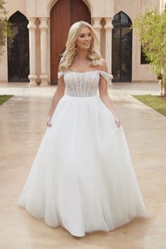 a woman in a white wedding dress standing on a patio with an archway behind her