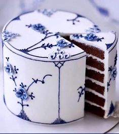 a white and blue cake sitting on top of a plate next to a piece of cake