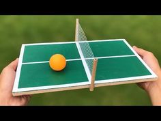 a ping pong table with an orange on it in front of a green field