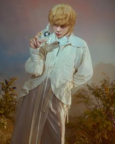 a woman with blonde hair holding a flower in her hand