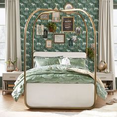 a bedroom with green and white wallpaper, a gold bed frame and pictures on the wall