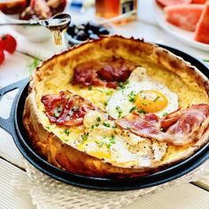 an omelet with bacon, eggs and ham on it is sitting on a table