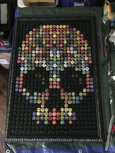 a table topped with lots of different colored buttons on top of a black tray covered in plastic