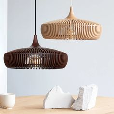 two wooden lamps hanging from the ceiling above a table with rocks and cups on it