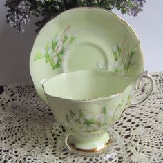 two cups and saucers sitting on a doily next to a potted plant