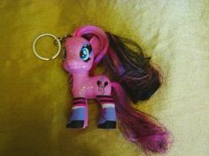 a pink pony keychain laying on top of a bed