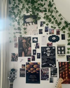 a white wall covered in posters and pictures next to a window with green ivy growing on it