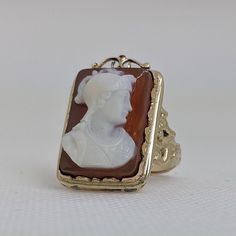 This gorgeous vintage cameo ring is beautifully crafted in a solid 14k gold frame with details at every angle. The victorian style is likely a 1930-1950s creation. In the center is a carved shell cameo of a Roman soldier. The cameo is in excellent condition and the sturdy ring measures approximately 26.45mm tall (including gold filigree fame) x 17.37mm wide. The ring is currently a ring size 7.5 but can be resized by your trusted local jeweler. A bold statement ring for men and women who love an Vintage Carved Signet Ring For Formal Occasions, Vintage Carved Rings For Formal Occasions, Vintage Carved Wedding Signet Ring, Vintage Carved Rings For Formal Events, Victorian Style Cameo Signet Ring For Formal Occasions, Vintage Cameo Rings For Formal Events, Cameo 14k Gold Rings For Collectors, Vintage Cameo Rings For Formal Occasions, Vintage Carved Signet Ring