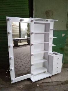 a large white cabinet with lights on it's doors and drawers in front of a green wall