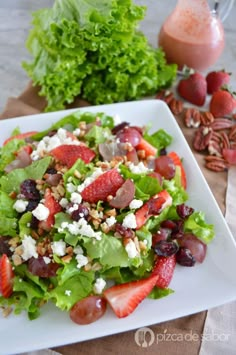 a salad with strawberries, grapes and feta cheese is on a white plate