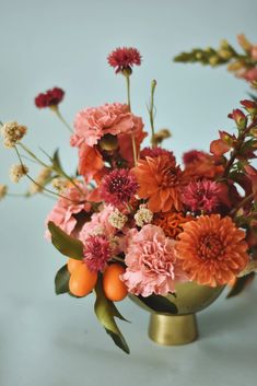 a vase filled with lots of flowers and oranges