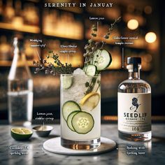 a glass filled with cucumber, lemon and herbs on top of a table