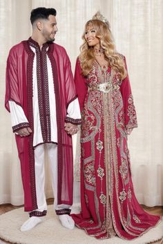 a man and woman standing next to each other on a rug in front of curtains