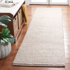 a white rug on the floor in front of a door with a potted plant next to it