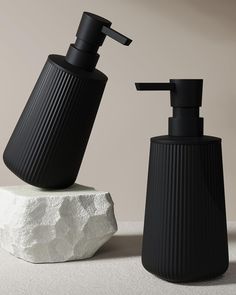 two black soap dispensers sitting next to each other on a white surface