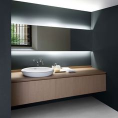 a bathroom with two sinks and a large mirror above the sink is lit by lights