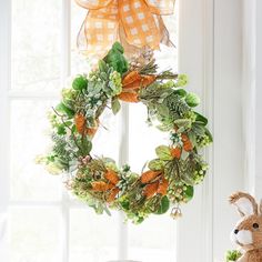 a stuffed animal sitting next to a wreath on a window sill