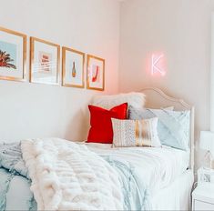 a white bed topped with lots of pillows next to pictures on the wall above it