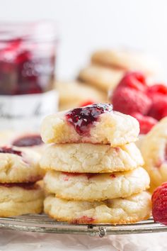 a stack of raspberry shortbread cookies on a plate with jam in the background