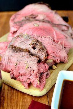 sliced meat sitting on top of a wooden cutting board