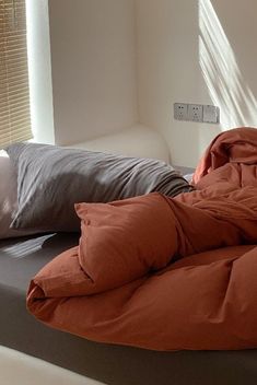 an unmade bed with two pillows on top of it and a pillow in the middle