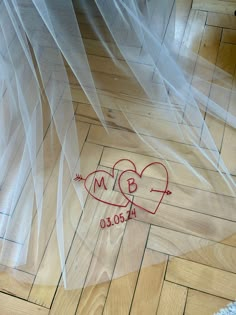 two hearts drawn on the floor in front of a wedding veil with writing underneath it