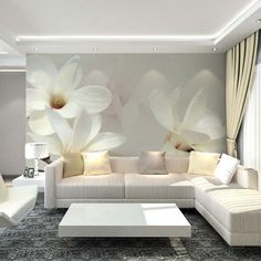 a living room with white furniture and large flowers on the wall behind it's couch