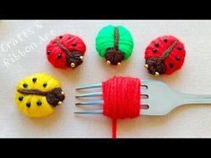 four little ladybugs are sitting on top of a fork with yarn wrapped around them