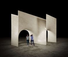 two people standing in front of a white structure with light coming from it's windows