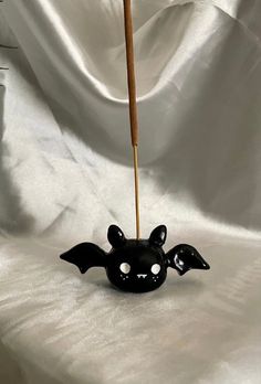 a black bat shaped vase with a wooden stick sticking out of it