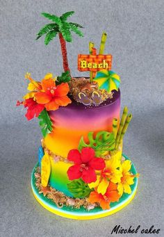 there is a multi layer cake with flowers and palm trees on top that says beach