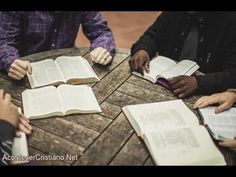 four people sitting at a table with open books