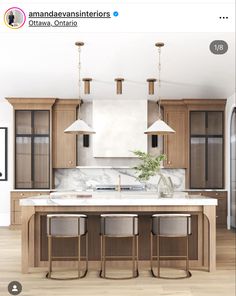 a kitchen with wooden cabinets and white marble counter tops, along with two pendant lights hanging from the ceiling