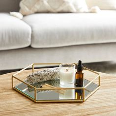 a table with a candle, glass bottle and mirror on it in front of a couch