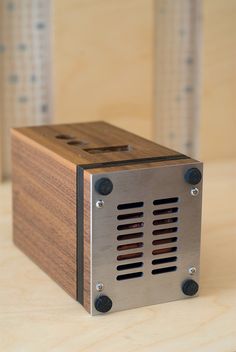 a metal and wood box sitting on top of a wooden table next to a wall