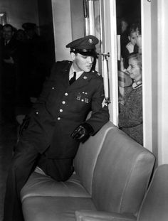 an old photo of a woman in uniform standing next to a door and talking on the phone