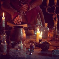 a table topped with lots of candles next to bottles and jars on top of it