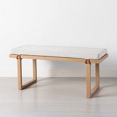 a bench sitting on top of a hard wood floor next to a white painted wall